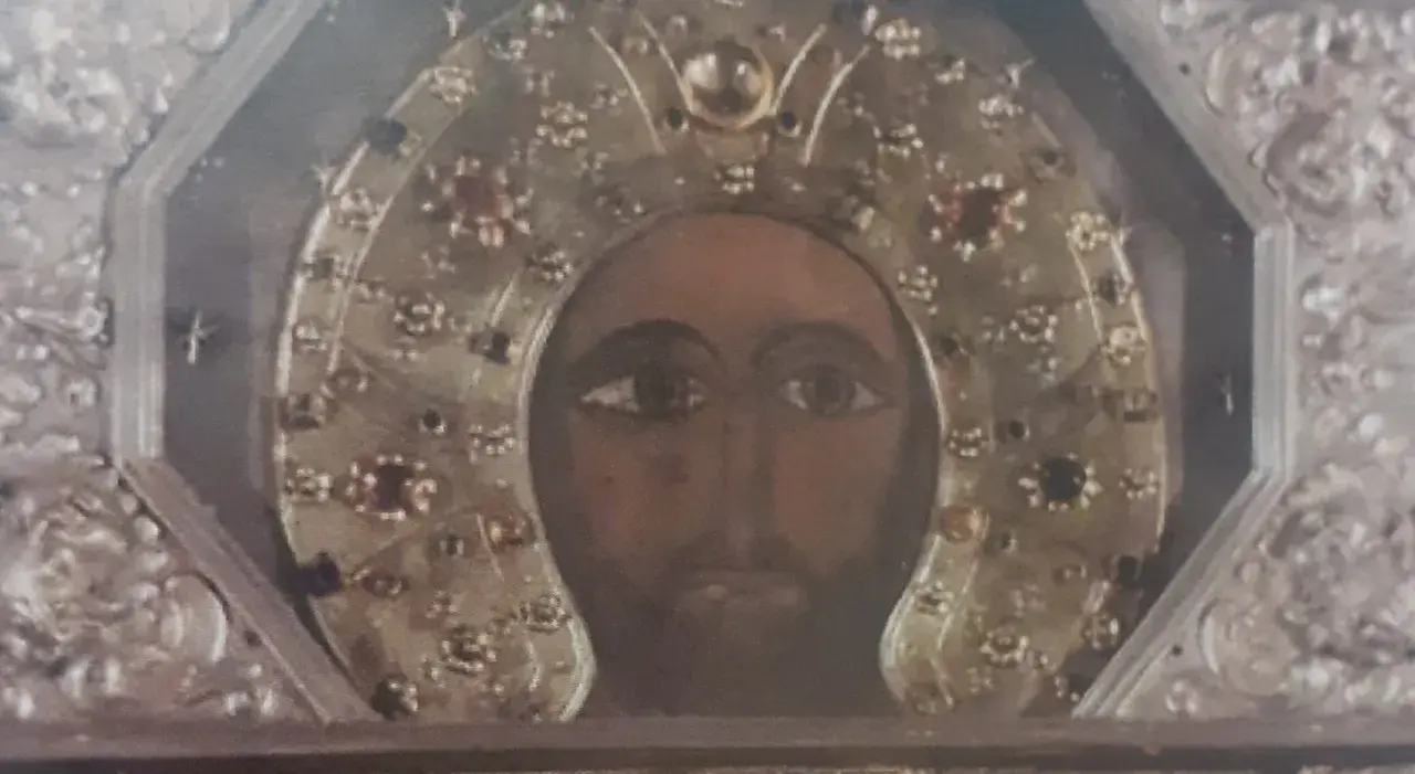 Volto del Cristo Acheropita, icona bizantina con aureola decorata da gemme e ricami dorati, incastonata in una cornice argentata.
