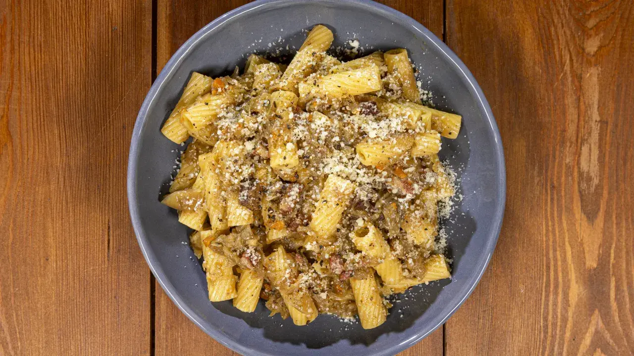 Piatto di pasta con sugo ricco e formaggio grattugiato, una deliziosa finta genovese napoletana.
