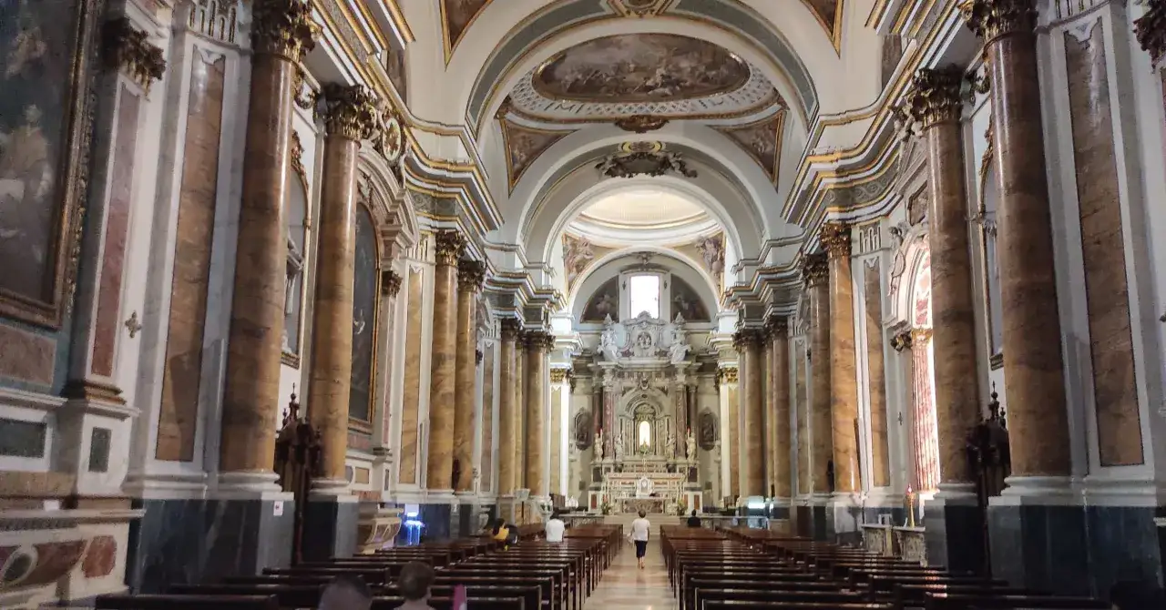 Interno di una chiesa barocca, con colonne marmorizzate, affreschi sul soffitto e un altare imponente. Un luogo dove si narra sia avvenuto un miracolo eucaristico a Lanciano.