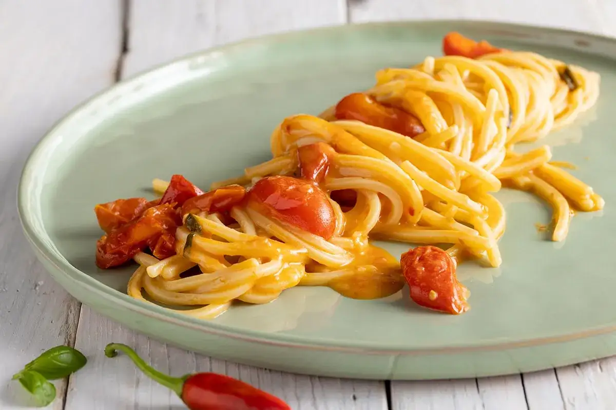 Un piatto di linguine allo scarpariello, condite con pomodorini succosi e un tocco piccante di peperoncino.