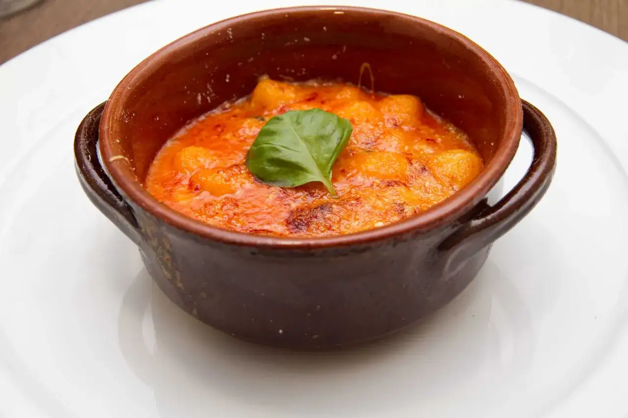 Gnocchi alla sorrentina, un classico della tradizione, serviti in cocotte con pomodoro, mozzarella filante e basilico fresco.