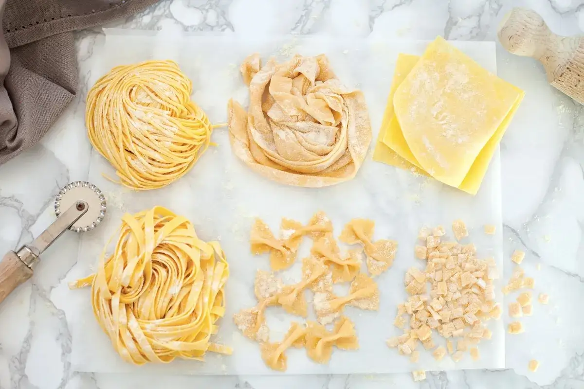 Vari tipi di pasta fresca: tagliatelle, farfalle, sfoglie per lasagne e maltagliati. Il maccarone significato è un mondo di sapori.