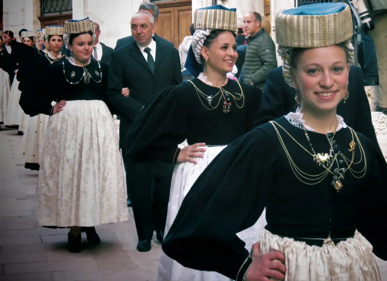 Giovani donne in sfilata con un vestito tipico abruzzese donna, cappelli decorati e gioielli d'oro.