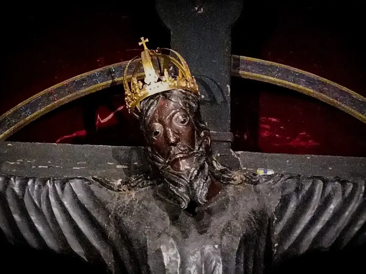Il volto di Gesù, con la corona d'oro, appare sofferente e regale sulla croce.