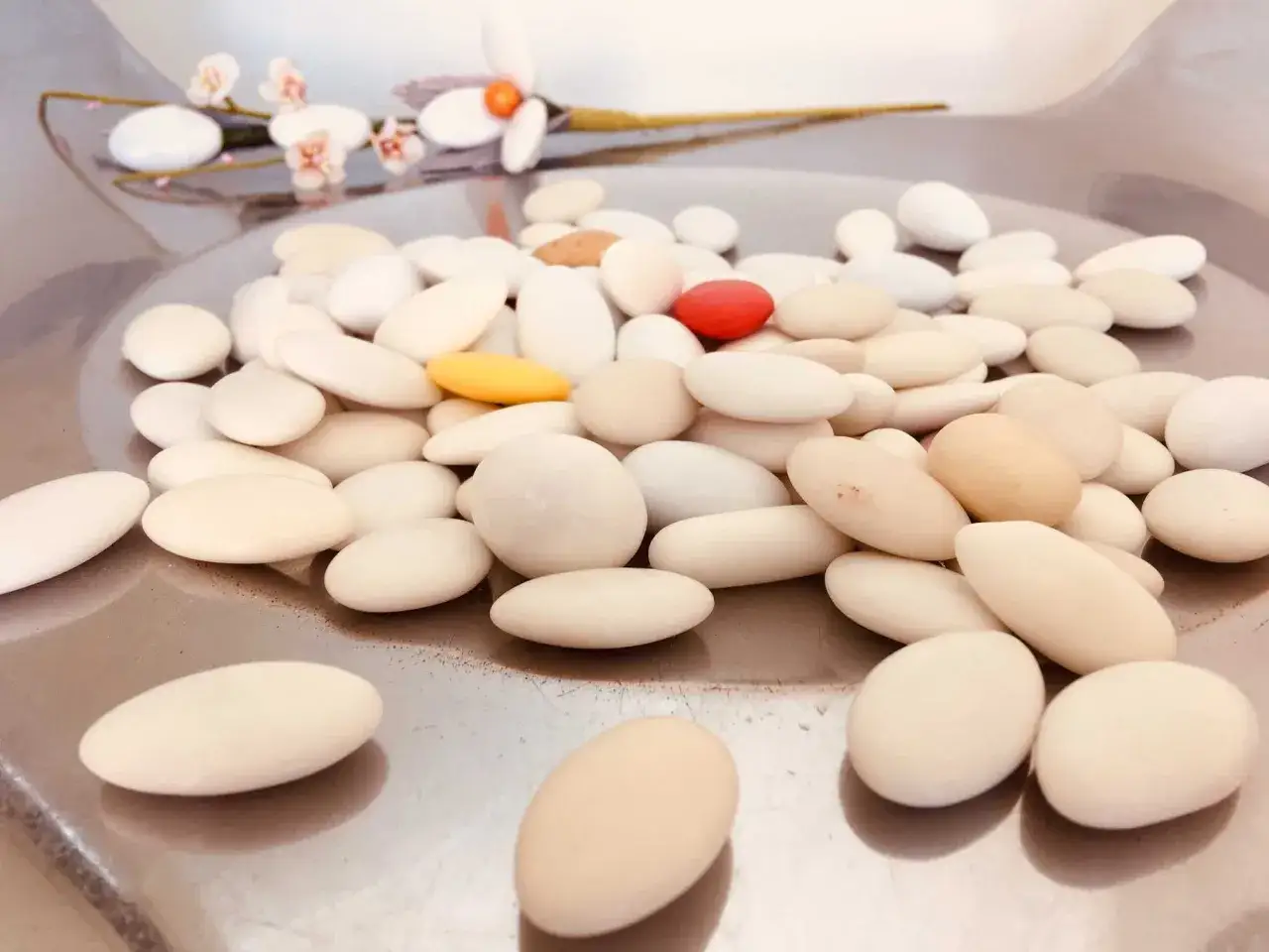Confetti bianchi e colorati, tra cui un rosso acceso e un giallo, che ricordano i dolci tipici di Sulmona, su un vassoio metallico.