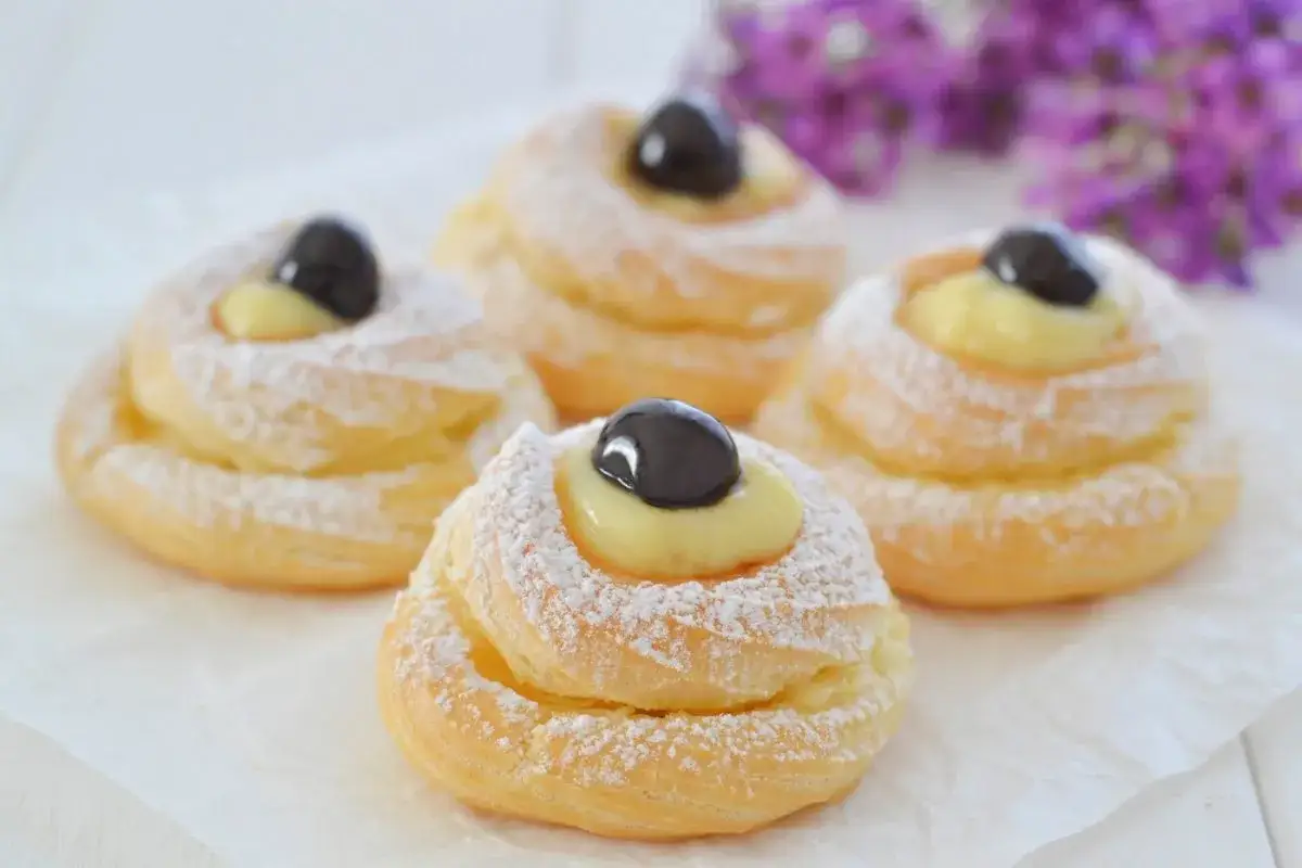 Zeppole di San Giuseppe, dolci fritti cosparsi di zucchero a velo, con crema pasticcera e amarena. La ricetta delle zeppole di San Giuseppe &egrave; un classico.