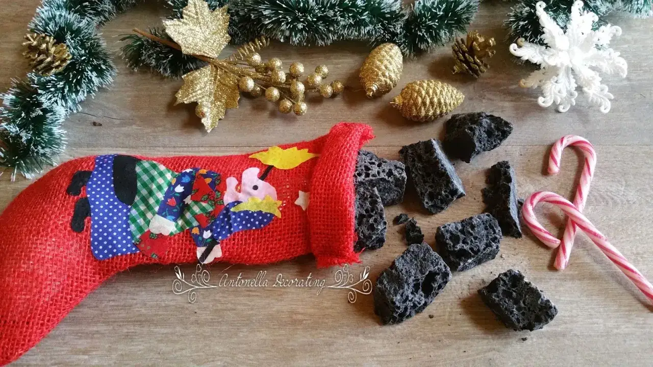 Un sacco della Befana rosso, decorato con stoffe colorate, rovescia pezzi di carbone. Un messaggio della Befana per i monelli?