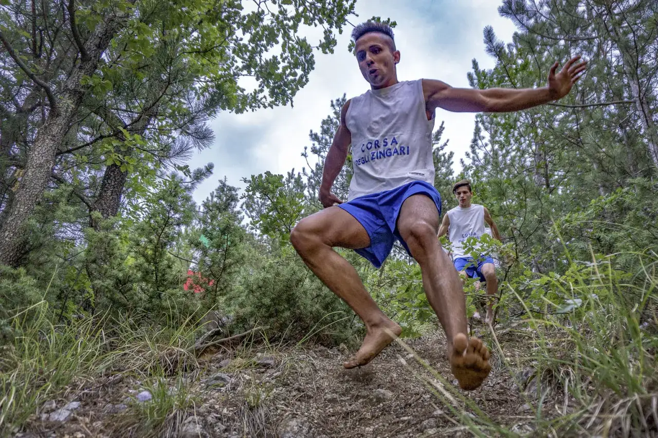 Due giovani atleti corrono a piedi nudi nel bosco, partecipando alla