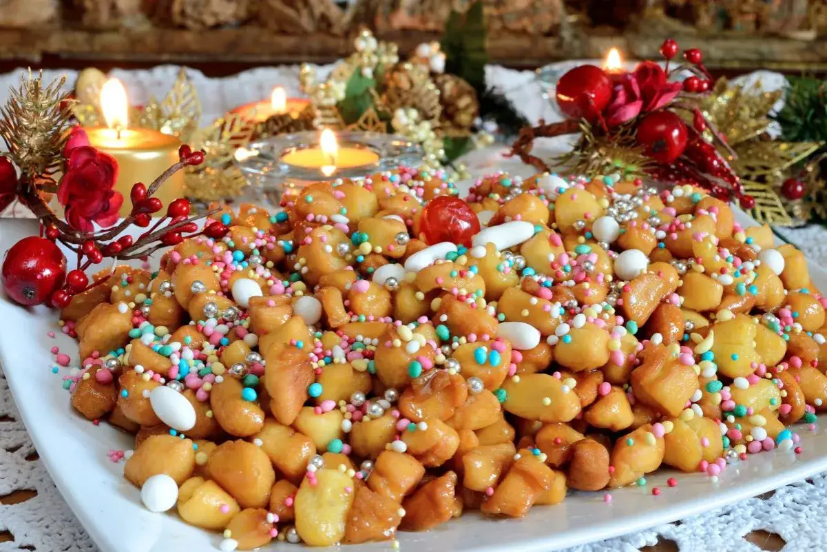 Dolci natalizi colorati, perfetti per quando è Epifania, con candeline accese e decorazioni festive sullo sfondo.