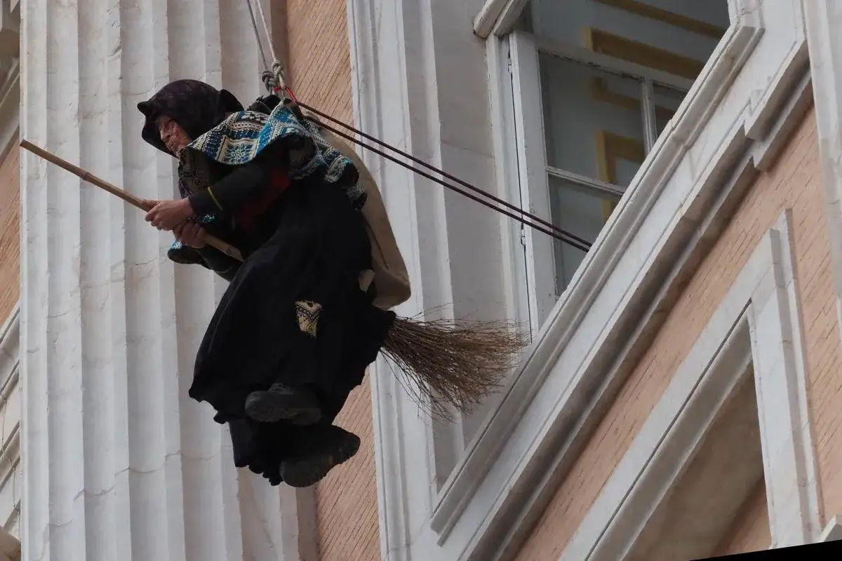 La Befana vera cattiva vola su una scopa, con un sacco pieno di carbone, pronta a dispensare dolci o carbone ai bambini.