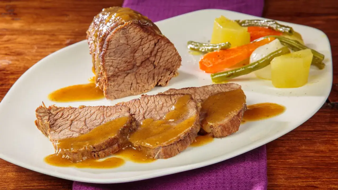 Fette di coda di vitello alla genovese, succulenta e profumata, servita con patate, carote e fagiolini.