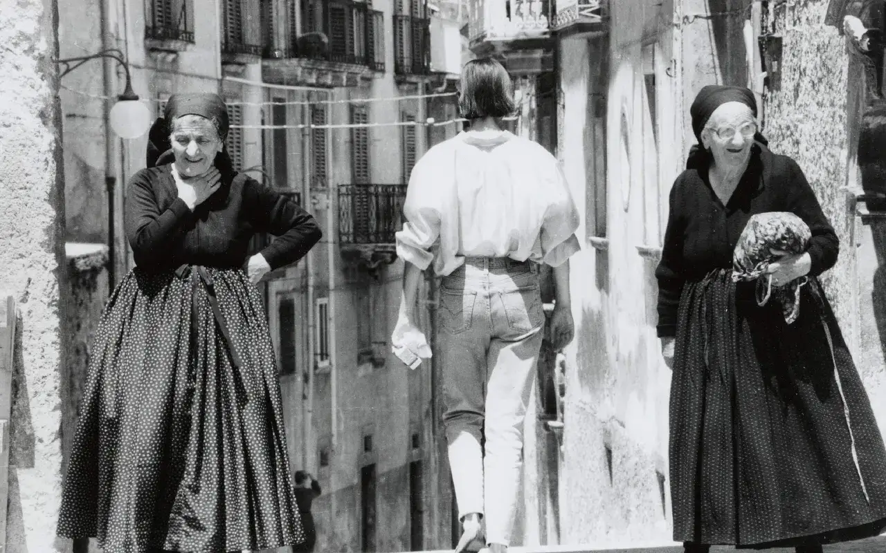 Due donne anziane in vestito tipico abruzzese donna passeggiano in un vicolo. Una tiene un fagotto.