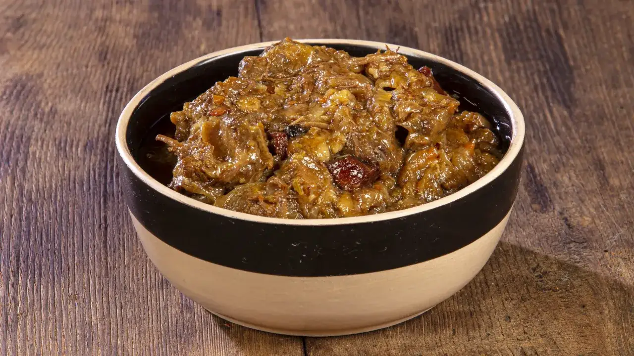 Un saporito stufato di carne, un'autentica ricetta genovese alla napoletana, servito in una ciotola su un tavolo di legno.
