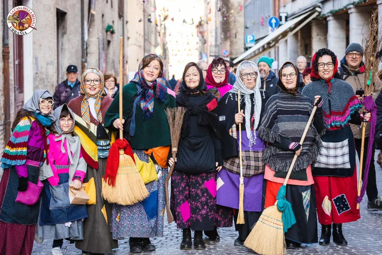 Un gruppo di donne e bambine vestite da Befana, con scope e sacchi, sfilano per le strade di Urbania, la casa della Befana.