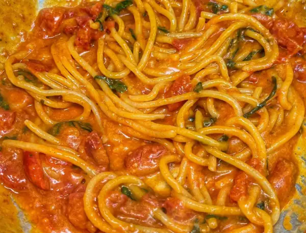 Un primo piatto invitante di linguine allo scarpariello, con pomodorini succosi e basilico fresco in una salsa cremosa.