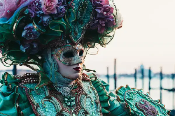Una maschera veneziana elaborata, con fiori e perle, evoca la storia delle maschere di carnevale.