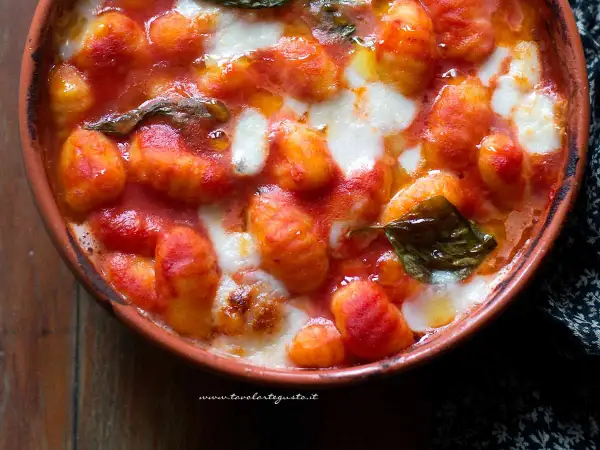 Gnocchi alla napoletana fumanti in terracotta, con pomodoro filante e basilico fresco. Un abbraccio di sapori autentici.