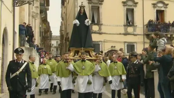 Processione a Sulmona con la Madonna che scappa, portata a spalla da uomini in verde e bianco, mentre i carabinieri sorvegliano.