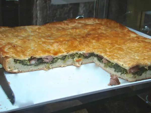 Pizza ripiena salsiccia e friarielli, un classico napoletano dal sapore intenso. La pasta dorata racchiude un cuore verde e saporito.