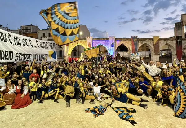 Folla festante in costume, bandiere sventolano, un'atmosfera di festa per la giostra cavalleresca Sulmona.