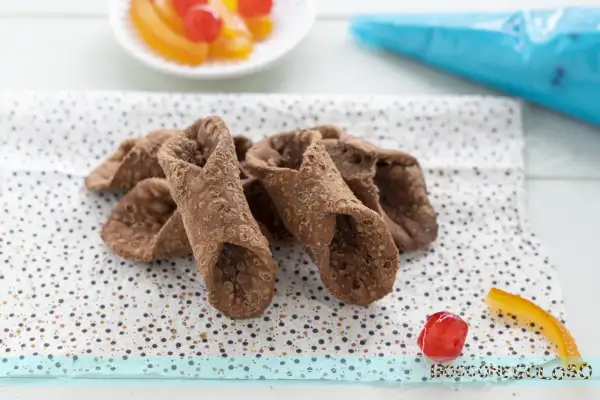 Scorza cannoli siciliani ricetta originale: croccanti involucri pronti per essere farciti, con canditi e ciliegina a lato.