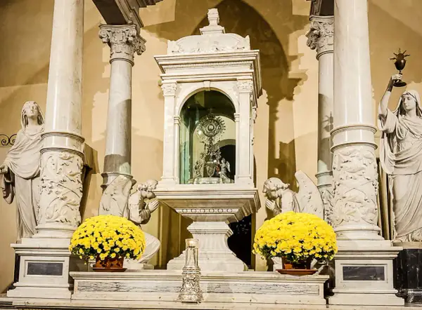 Altare con ostensorio scintillante, angeli adoranti e fiori gialli, evocando un miracolo eucaristico.