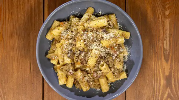 Piatto di pasta con sugo ricco e formaggio grattugiato, una deliziosa finta genovese napoletana.